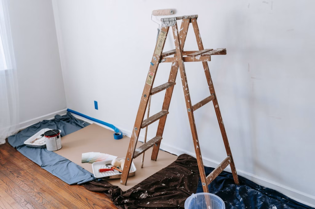 A room under renovation with a wooden ladder and paint materials, ready for a makeover.